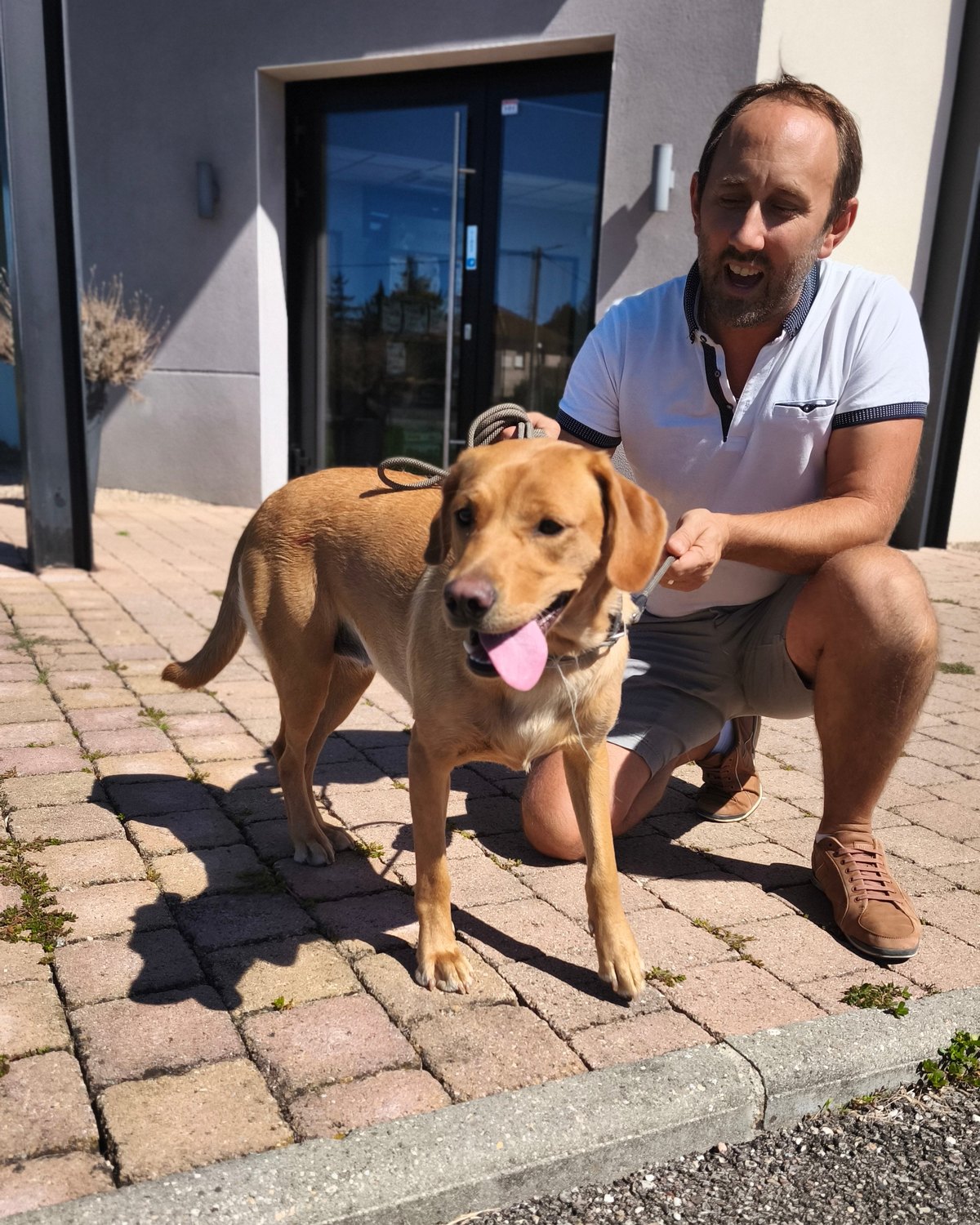 Propriétaire et son chien fauve devant l'entrée de la clinique